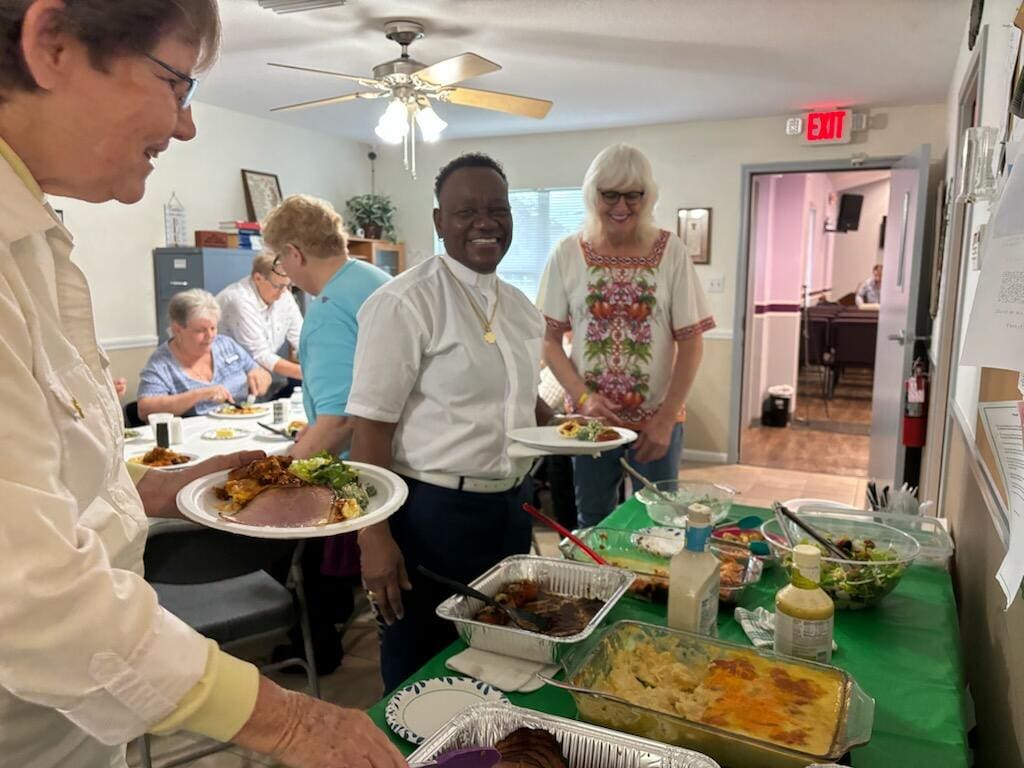 People serving food in a communal dining setting.