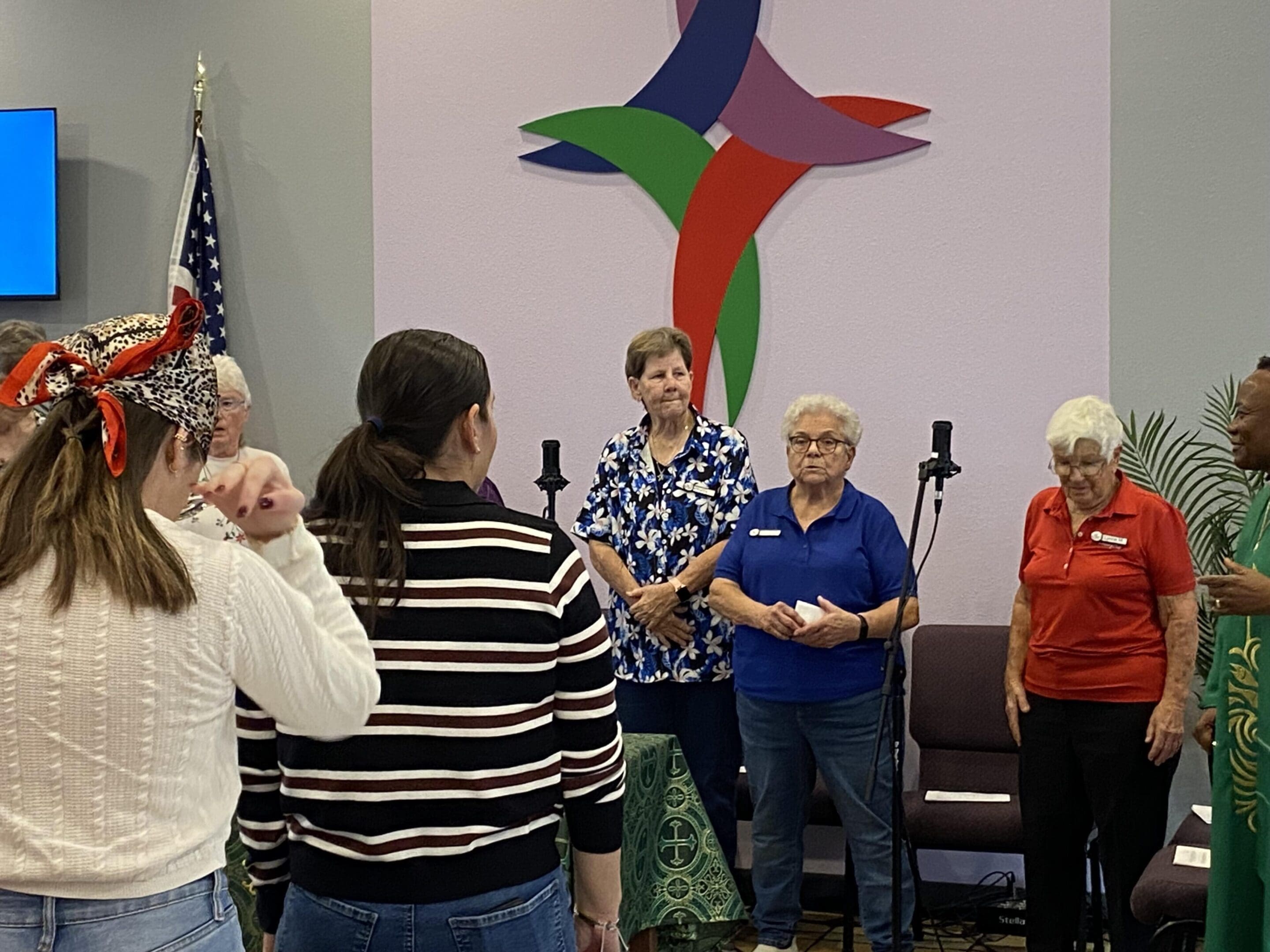 A group of people standing and listening at an indoor event.