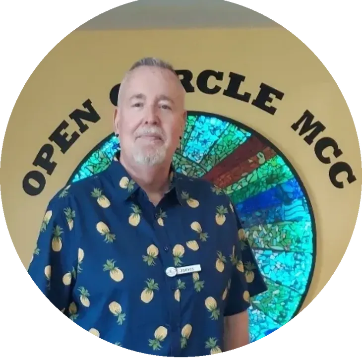 Man standing in front of a colorful circular sign with 'Open Circle MCC' text.