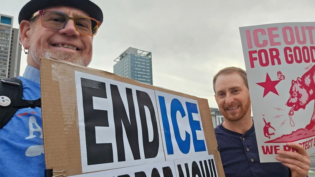 Two men holding a sign that says 'END ICE' protesting.