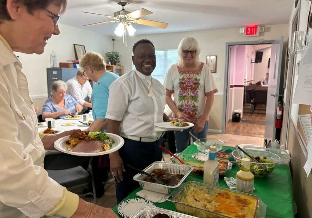 People serving food in a communal dining setting.